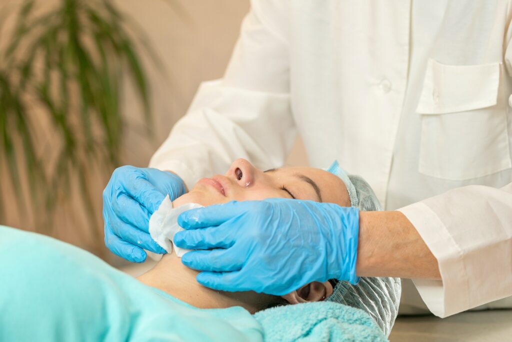esthetician wipes chemical peel on clients face